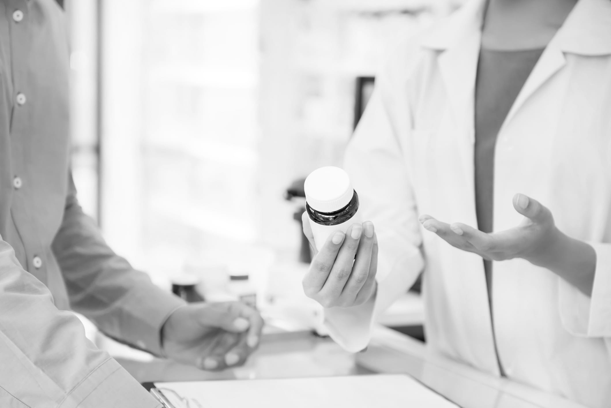 Pharmacist holding a container of medication, talking to a patient