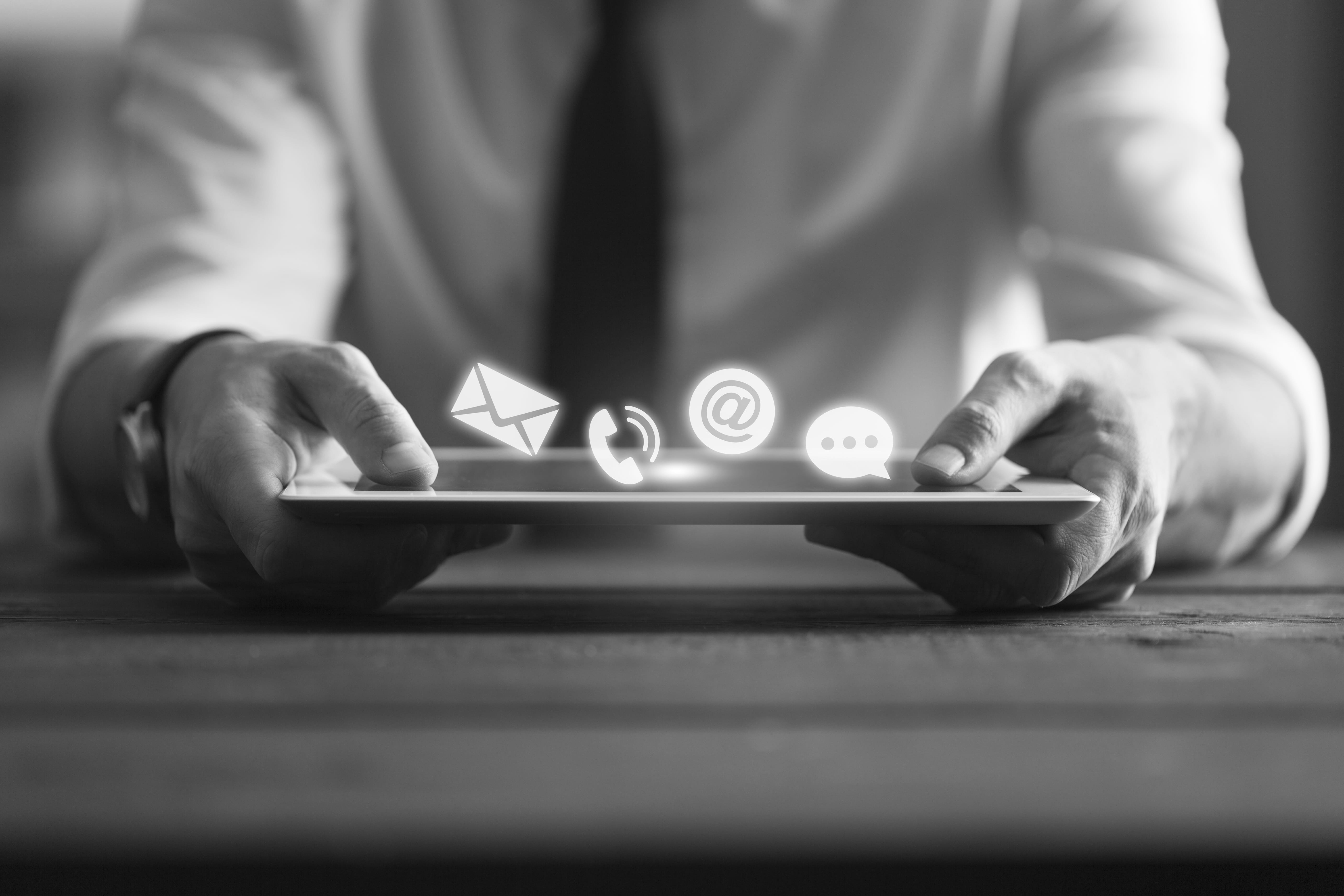 Hands typing on a tablet device, with icons coming off the screen.